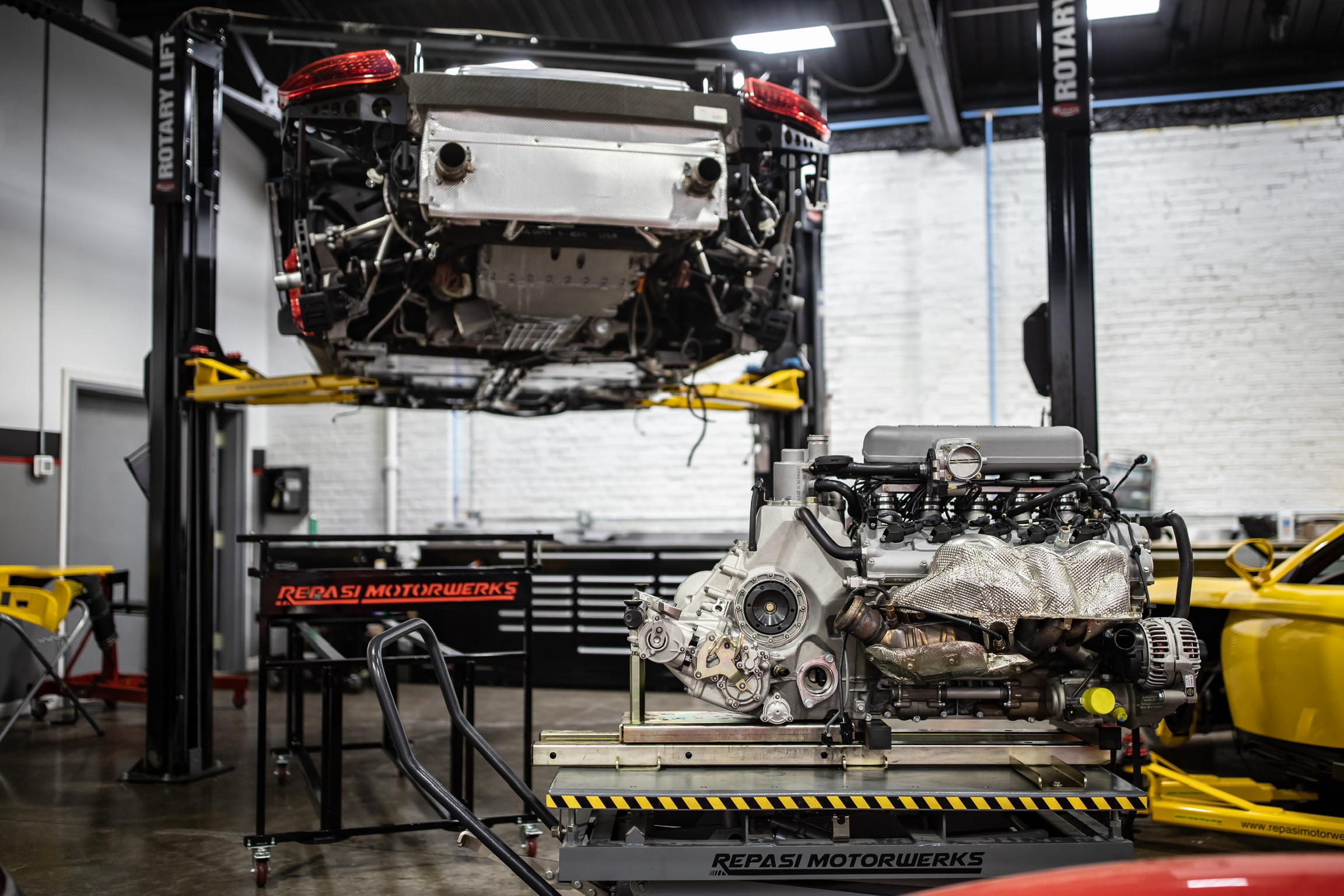 Porsche on a lift with its engine removed onto a cart below during engine-out major service at Repasi Motorwerks
