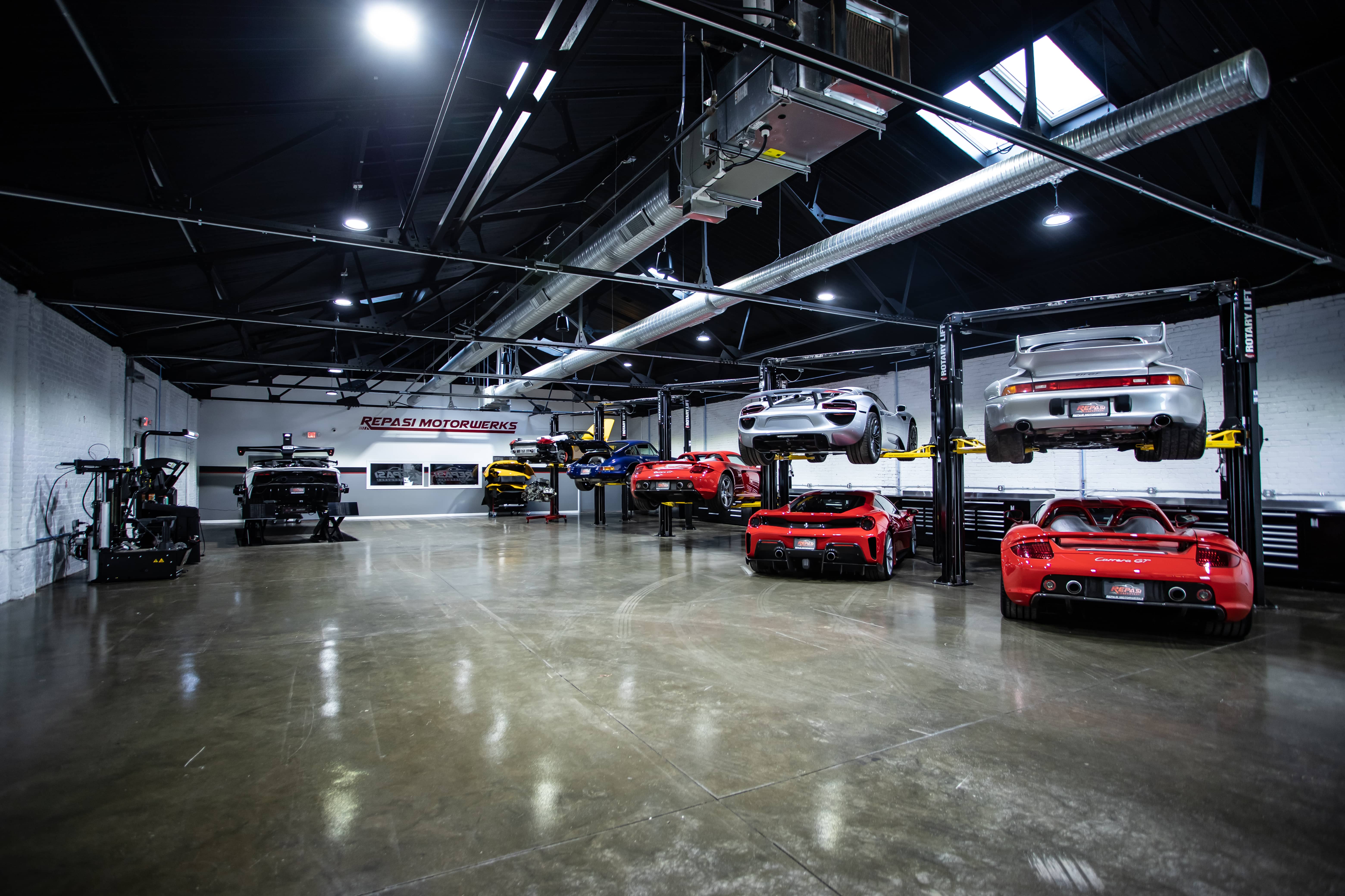 Wide view of multiple Porsche Carrera GTs and other Porsche GT cars on lifts at Repasi Motorwerks