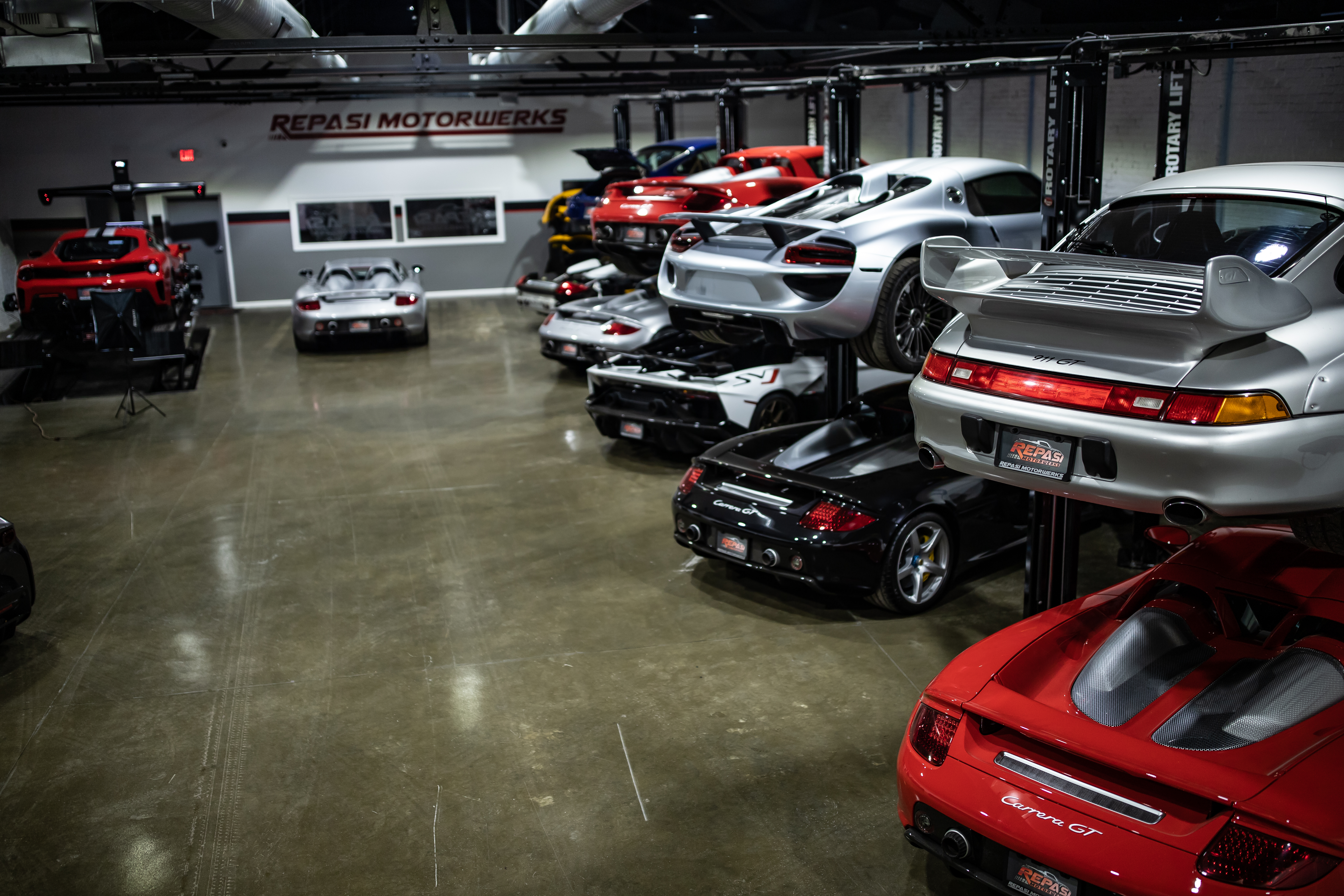 Wide overview of Repasi Motorwerks shop floor with multiple Carrera GTs and a LaFerrari on lifts
